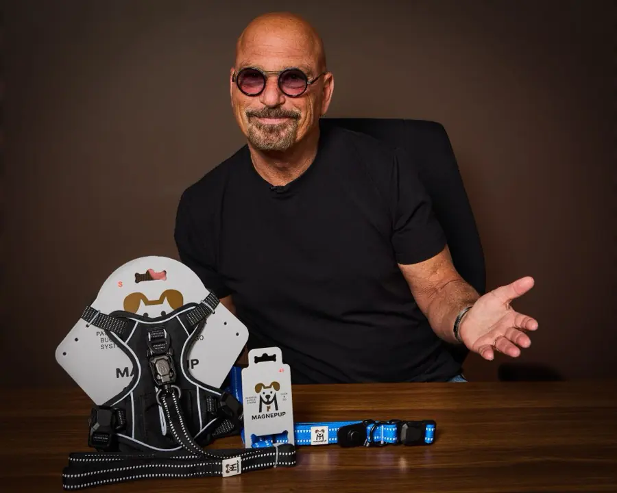 Howie Mandel seated beside a MagnePup harness, collar and leash.